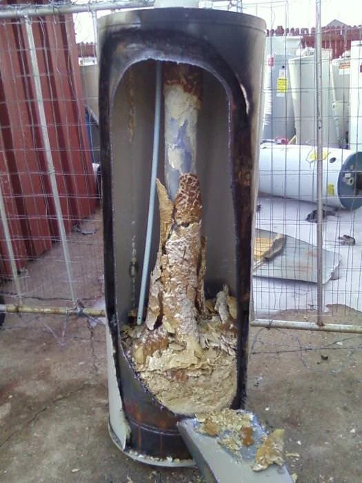 Cutaway of a water heater tank from a home with hard water showing a thick column of scale and sediment