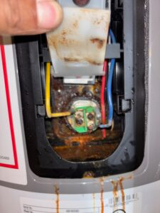 Corroded water heater heating element with rust dripping from the connection